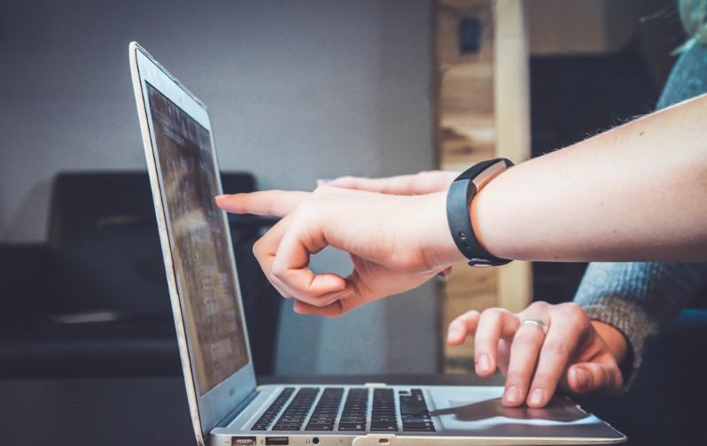 Two business professionals pointing at a laptop screen discussing RightAnswers vs Confluence